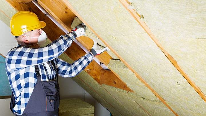 Man putting insulation into the eaves of a house