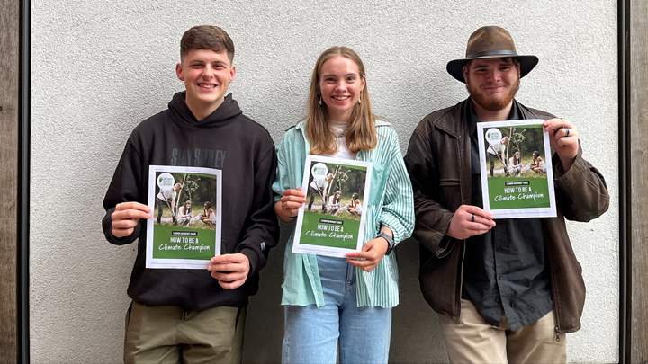 Three young people holding the guide on how to be a Climate Champion