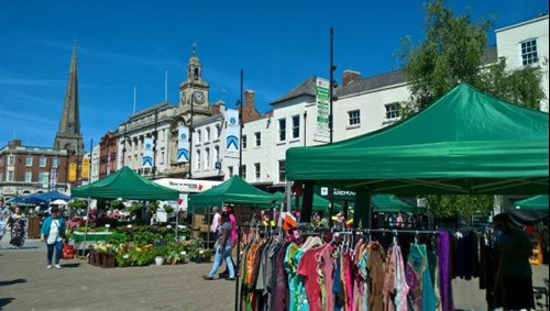 Market stalls in High street with clothes rails and vegetable displays